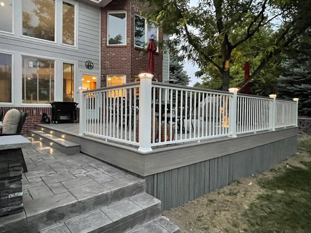 Luxury patio connected to a durable deck with sleek railings and built-in lighting in Commerce, Michigan