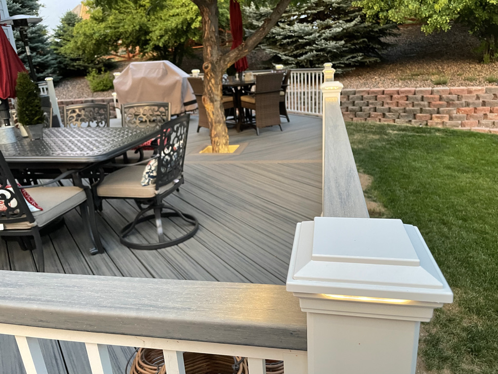 Outdoor Deck with white railing posts and built in lighting. Custom built by Elevated Outdoor Living Co in Commerce Michigan